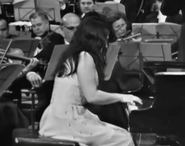 Martha Argerich performing at the piano, showing her seated posture, arm position, and wrist movement